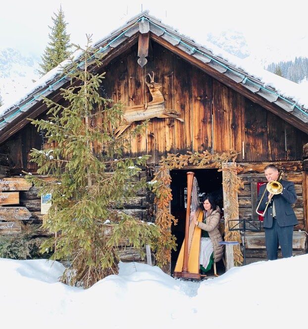Harpist plays at a snowy wedding under a wooden alpine cover.
