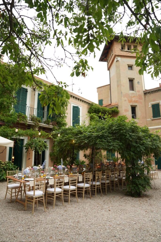 Italian Wedding dinner set up outside under greenery canopy