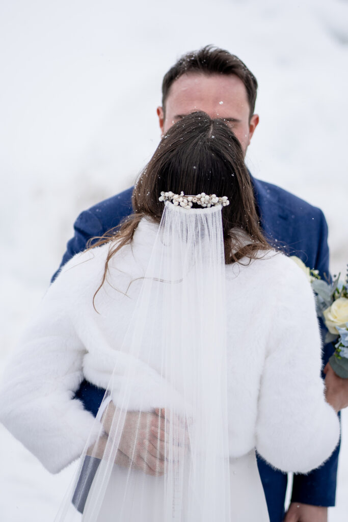 Bride and groom kiss in snow