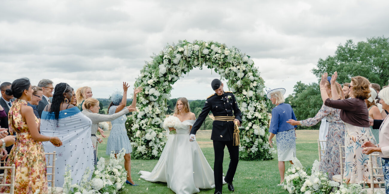 Wedding Planner Ella Hartig shares a photo of a Bride & Groom at Somerley House Wedding Ceremony in front of floral arch.