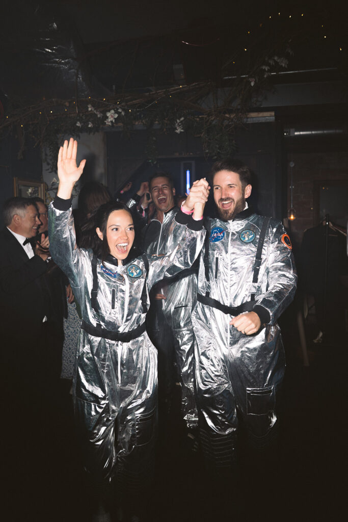 When it comes to how to choose your wedding photographer, ask how long they stay. Image shows a couple dressed in spacesuits for their evening party, which can easily be missed if your photographer has gone home.